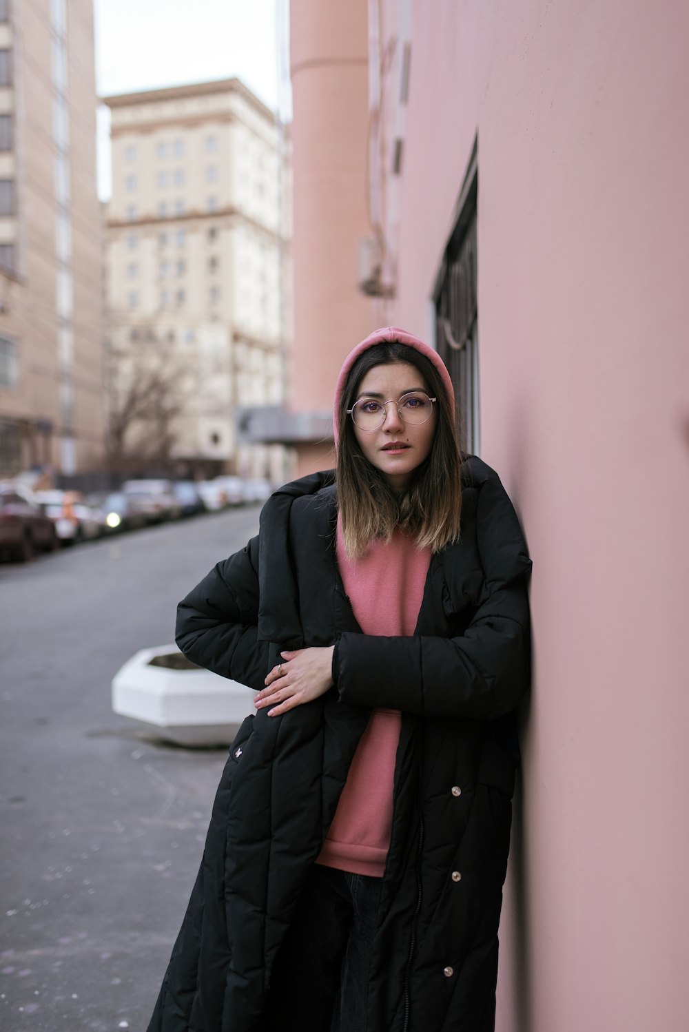 woman in black coat and red hijab standing near red wall during daytime