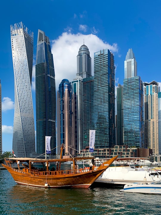 white and brown boat on dock near high rise buildings during daytime in Dubai Marina Walk - Emaar United Arab Emirates
