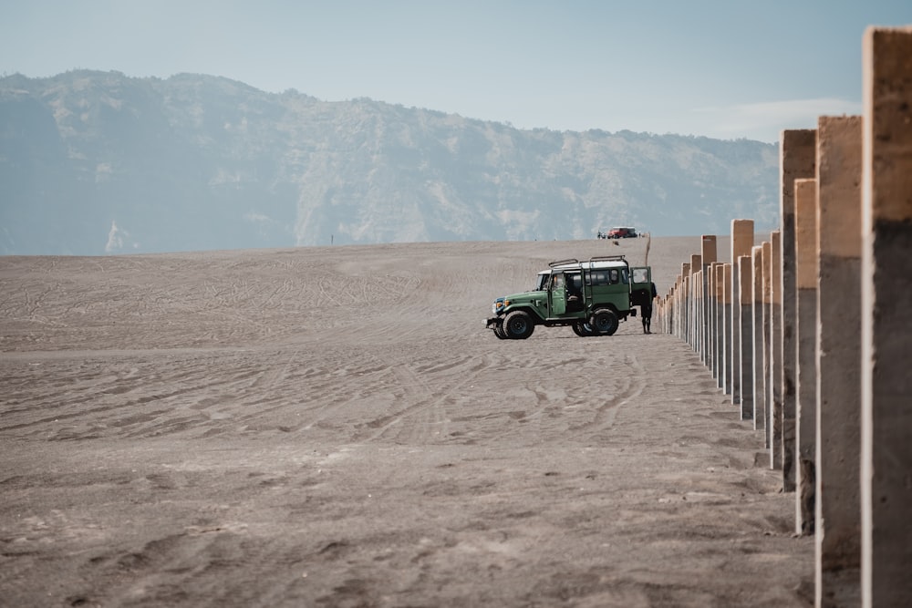 a green truck driving down a dirt road