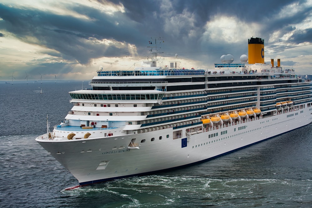 weißes Kreuzfahrtschiff auf See unter weißen Wolken und blauem Himmel tagsüber