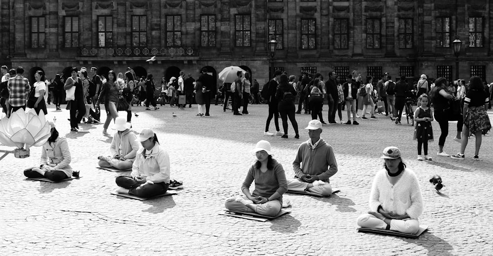 grayscale photo of people sitting on the street