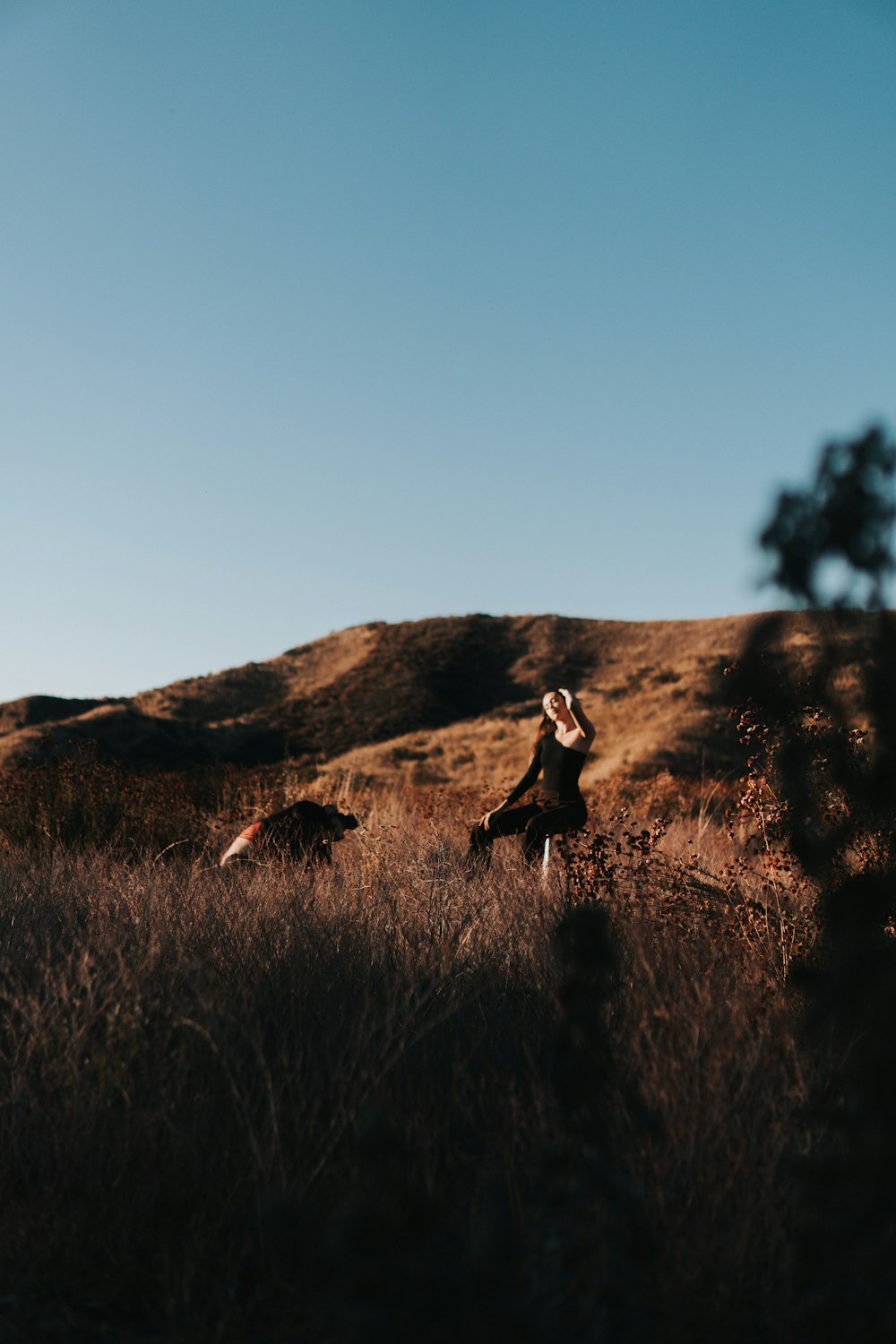 woman in black dress sitting on brown grass field during daytime