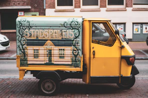 A sleek black and yellow Mercedes Vito minibus parked on a city street in The Hague at sunset.