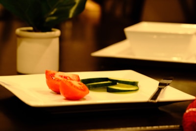 Bright kitchen scene with dried tomato slices on a white plate beside fresh herbs.
