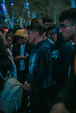 Volunteers in black hoodies illuminated by neon street signs, distributing food with focused determination.