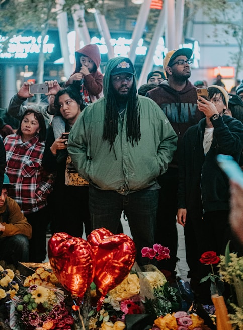 An intimate group gathering around a digital memorial screen sharing stories