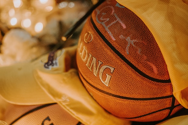 A close-up of a basketball partially covered by yellow fabric, with the Spalding logo prominently visible. The warm lighting creates a cozy atmosphere, highlighting the texture of the basketball's surface.