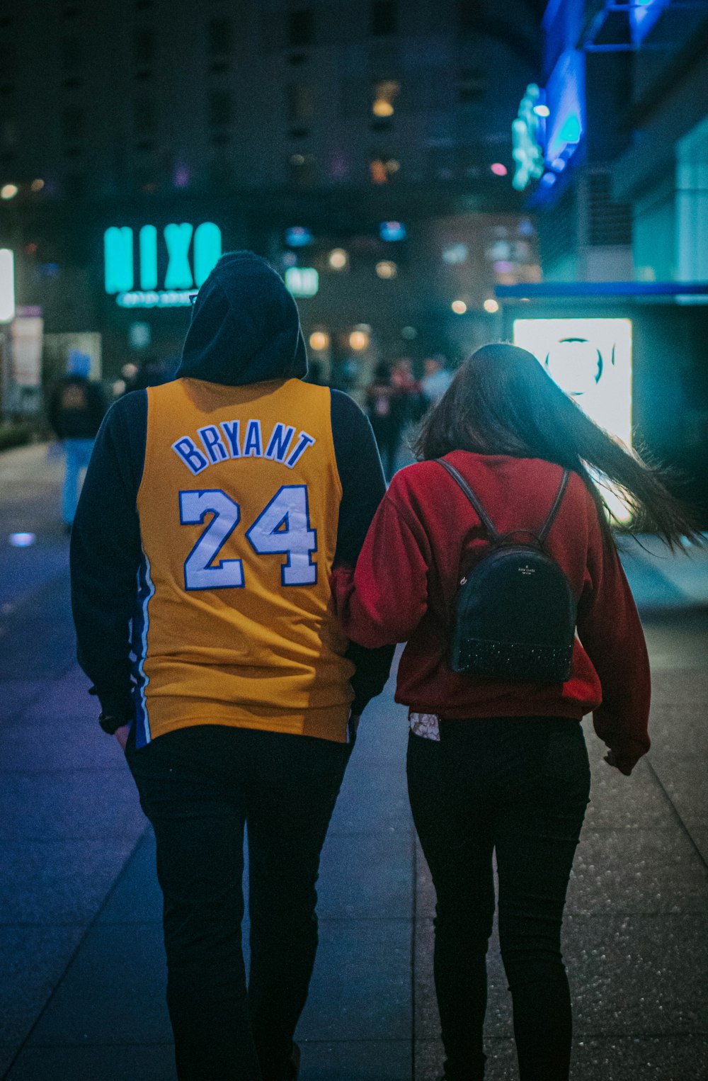 woman in orange and black hoodie standing in front of woman in black jacket