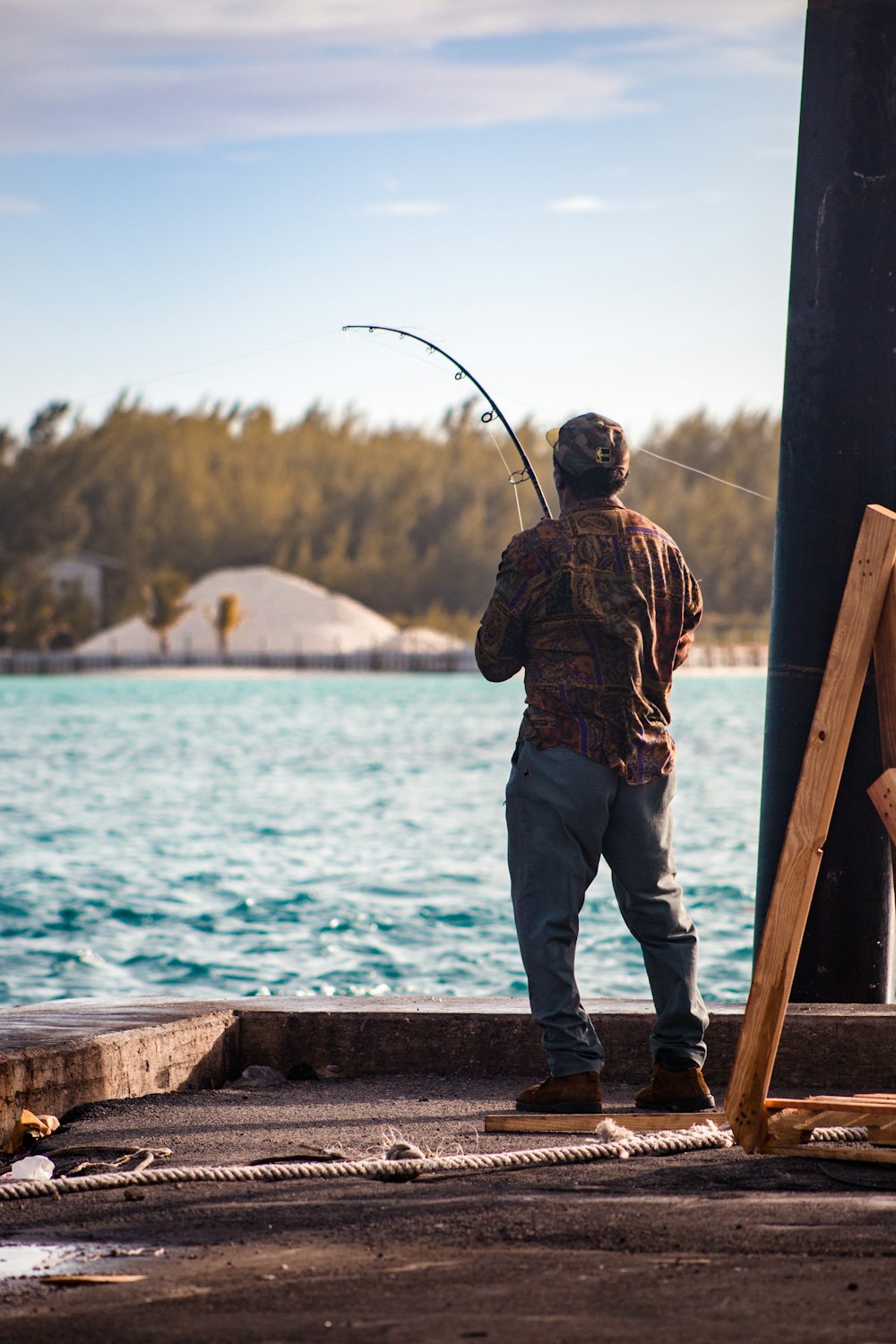 homme en veste de camouflage marron et noir et jean bleu en jean pêchant sur la mer pendant la journée