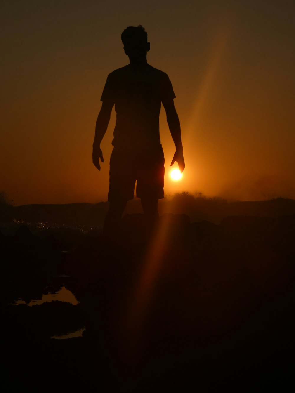 Silhouette eines Mannes, der bei Sonnenuntergang auf dem Felsen steht