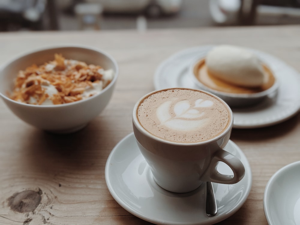 white ceramic mug with cappuccino on white ceramic saucer