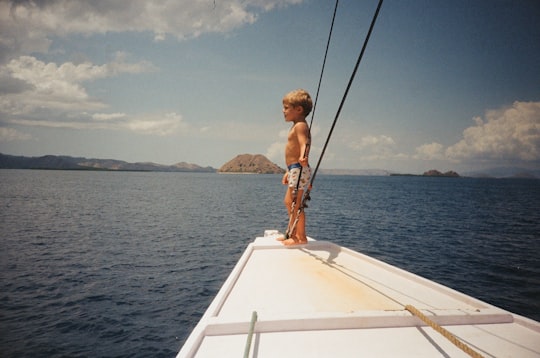 woman in brown bikini sitting on white boat during daytime in Komodo National Park Indonesia