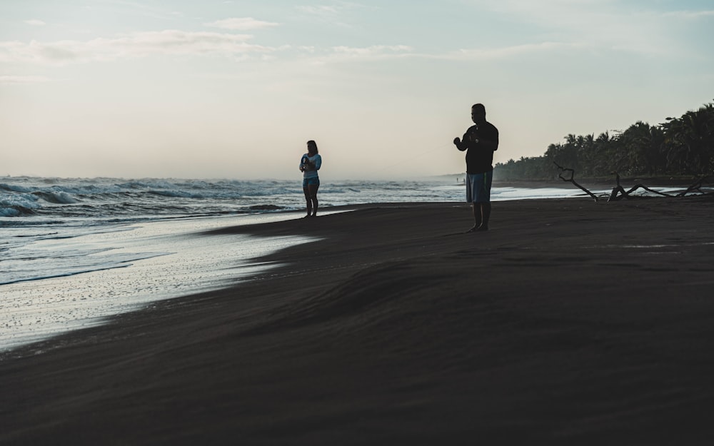 man and woman standing on beach during daytime