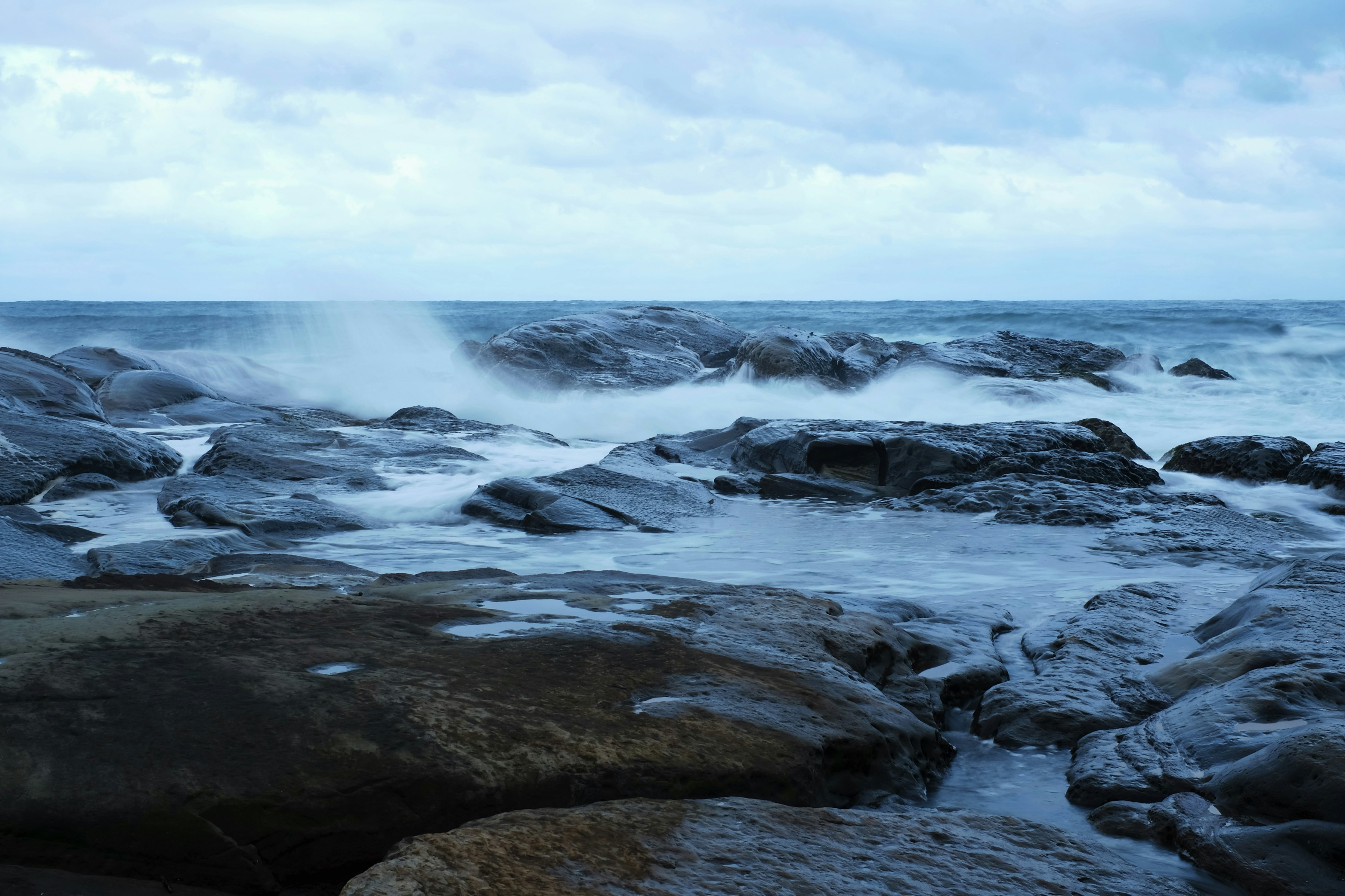 rocky shore under white clouds during daytime