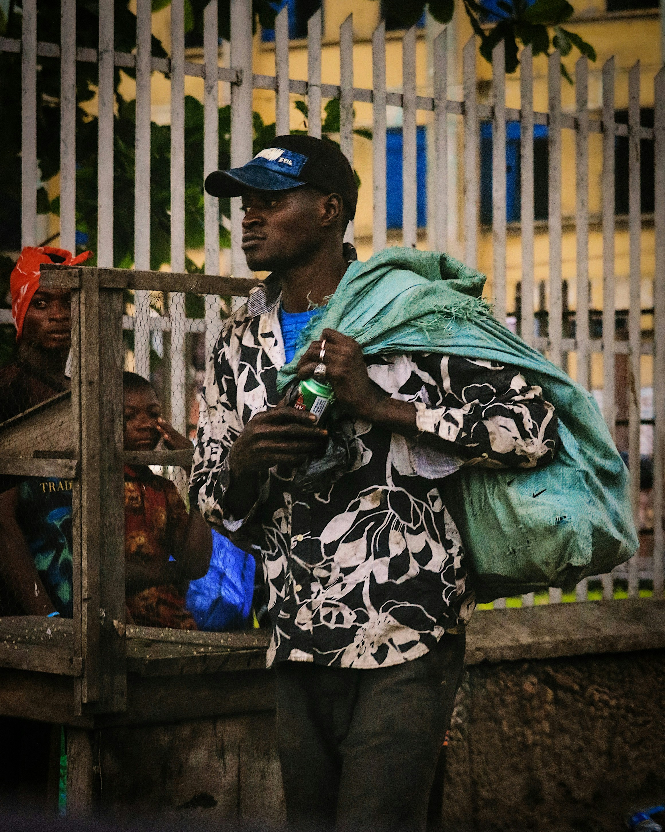 woman in black and white floral hijab standing beside brown wooden fence