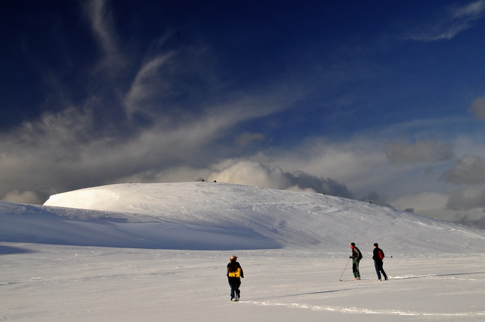 2 person walking on snow covered mountain under blue sky during daytime