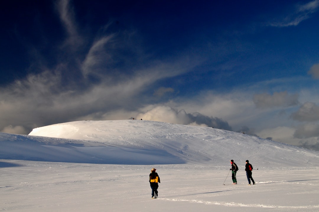 2 person walking on snow covered mountain under blue sky during daytime