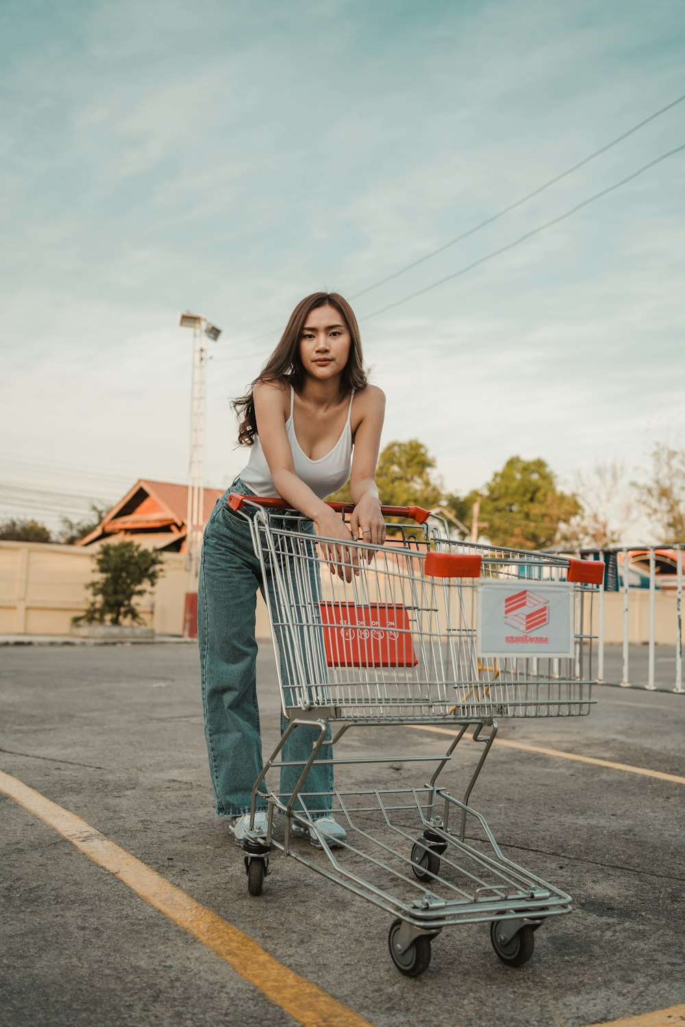 Frau in blauer Jeansjacke hält Einkaufswagen