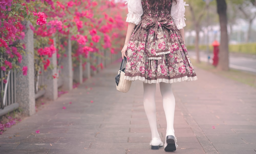 woman in white and pink floral dress walking on sidewalk during daytime