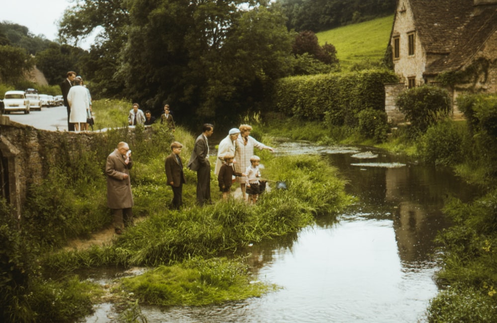 people standing on green grass near river during daytime