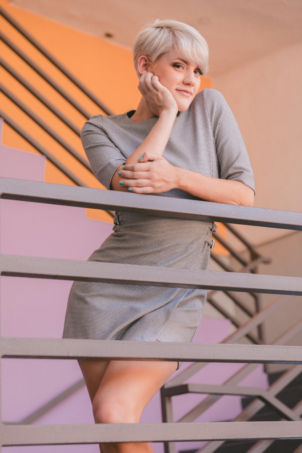 Mujer con camisa gris de manga larga apoyada en barandillas de madera marrón