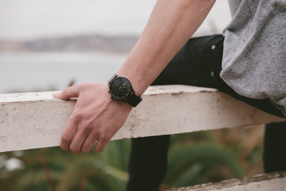 person wearing black round analog watch with black strap