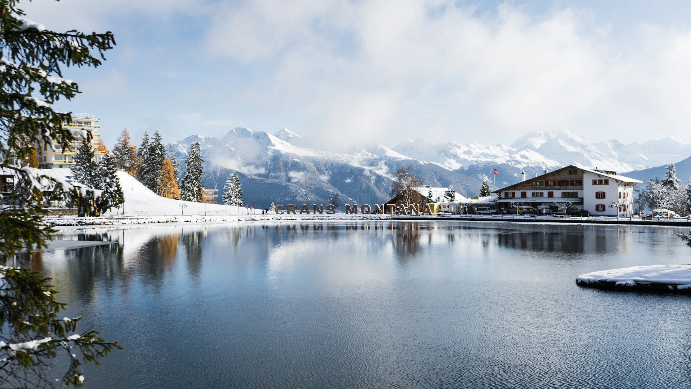 A snow-framed lake, forest, and mountains in Crans-Montana