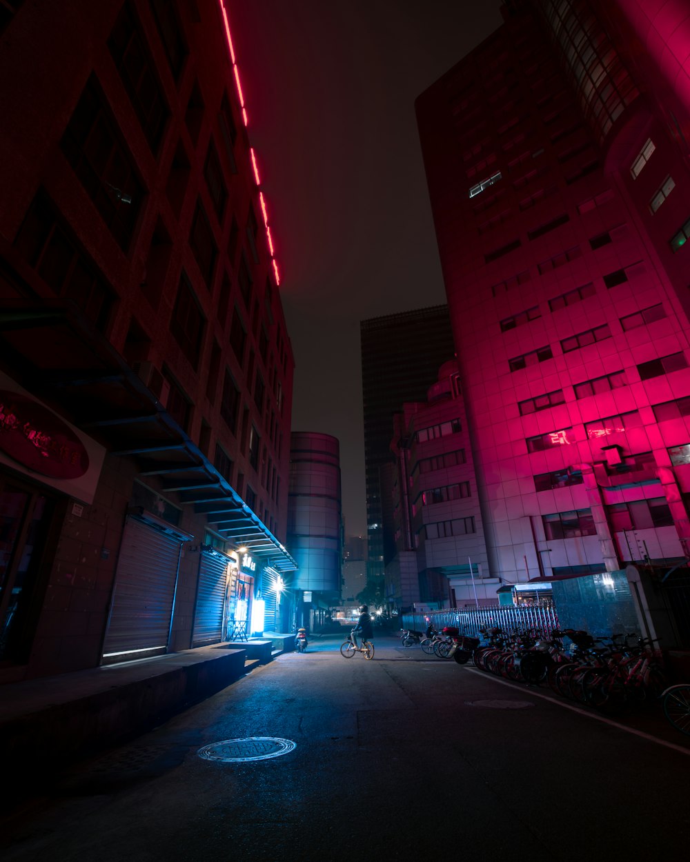 Coches aparcados a un lado de la carretera cerca de un edificio de gran altura durante la noche