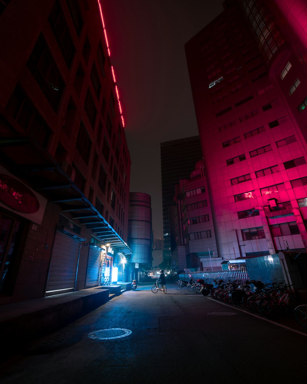 Voitures garées sur le bord de la route près d’un immeuble de grande hauteur pendant la nuit