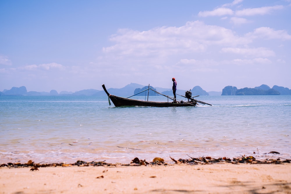 man in black shirt riding on blue boat on sea during daytime