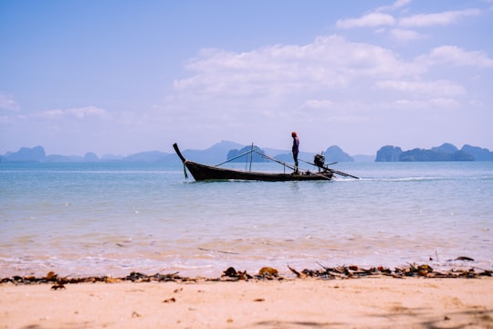 man in black shirt riding on blue boat on sea during daytime in Ko Yao Noi Ko Yao District Thailand