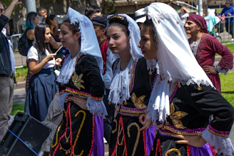 A group of women in traditional Croatian attire gathered around a table crafting embroidery.