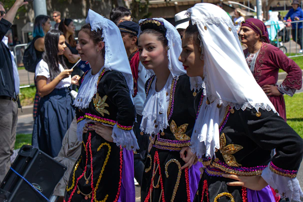 A group of women in traditional Croatian attire gathered around a table crafting embroidery.