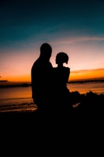 A romantic couple watching the sun dip below the horizon from their boat near the Gateway of India.
