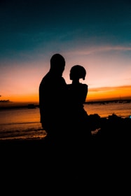 A romantic couple watching the sun dip below the horizon from their boat near the Gateway of India.
