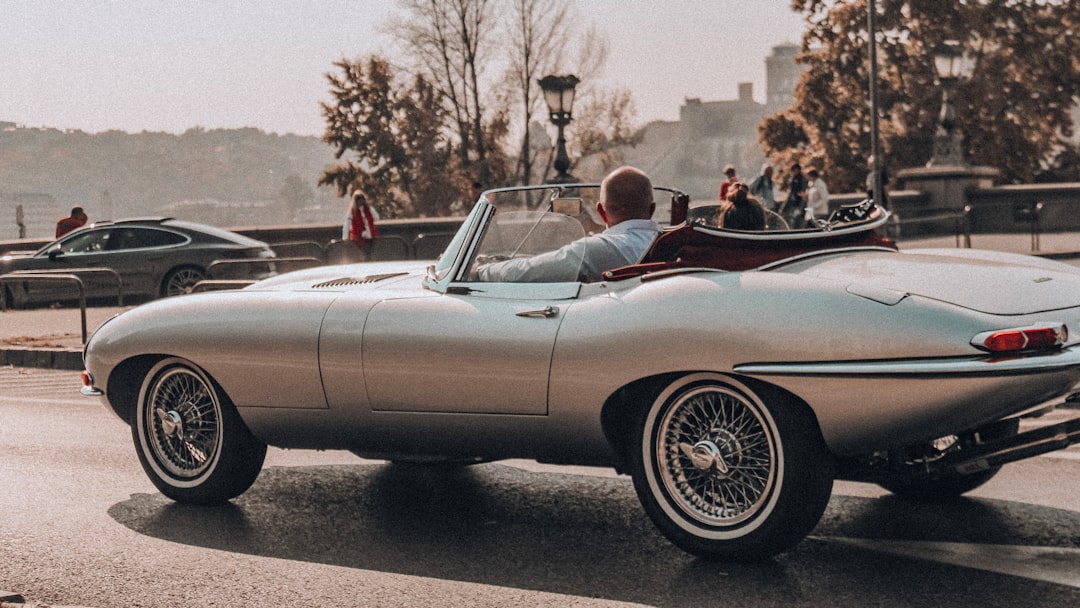 man in black jacket driving white convertible car