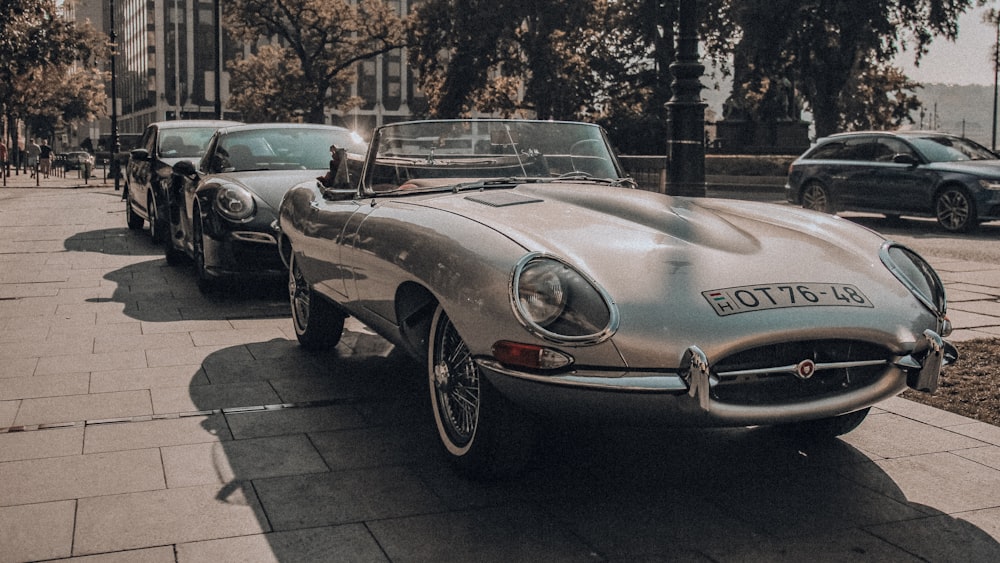 green classic car parked on sidewalk during daytime