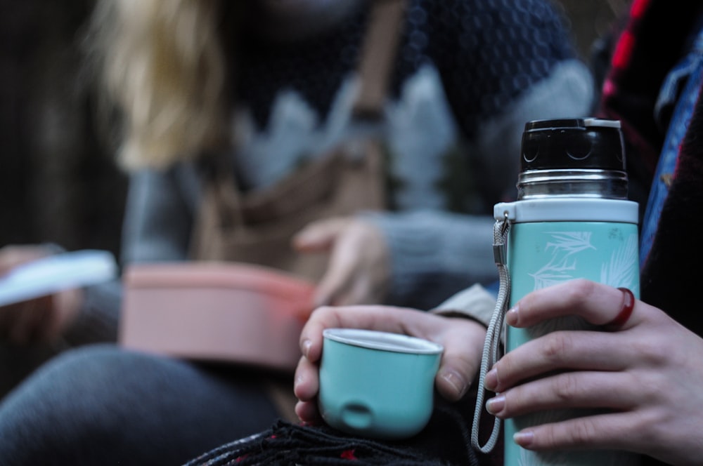 woman in black knit sweater holding blue ceramic mug