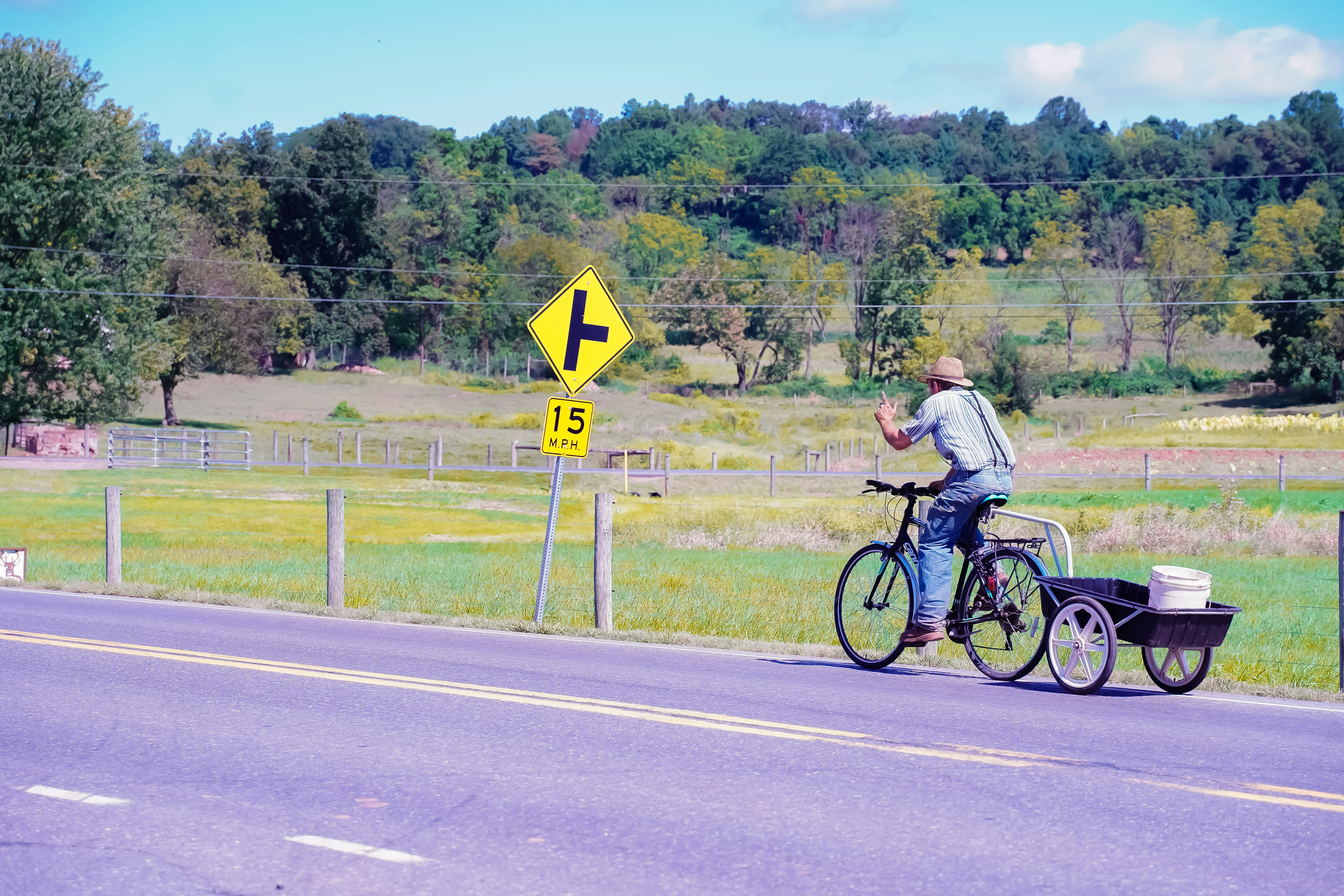 man in gray t-shirt riding bicycle on road during daytime