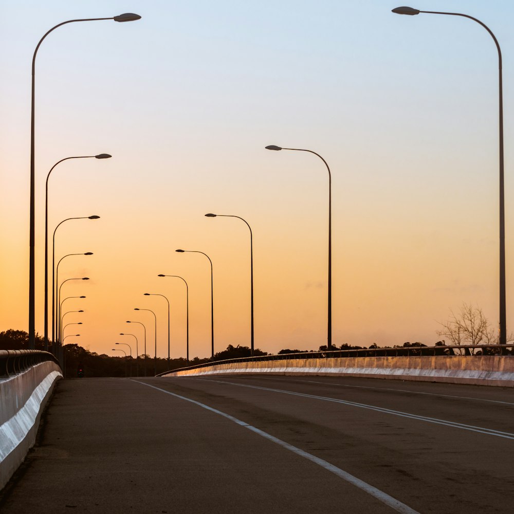 gray concrete road with light posts during daytime