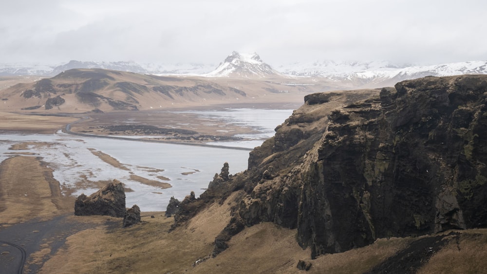 brown rocky mountain near body of water during daytime