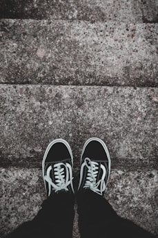 Minimalist sneakers resting on a concrete stairwell.