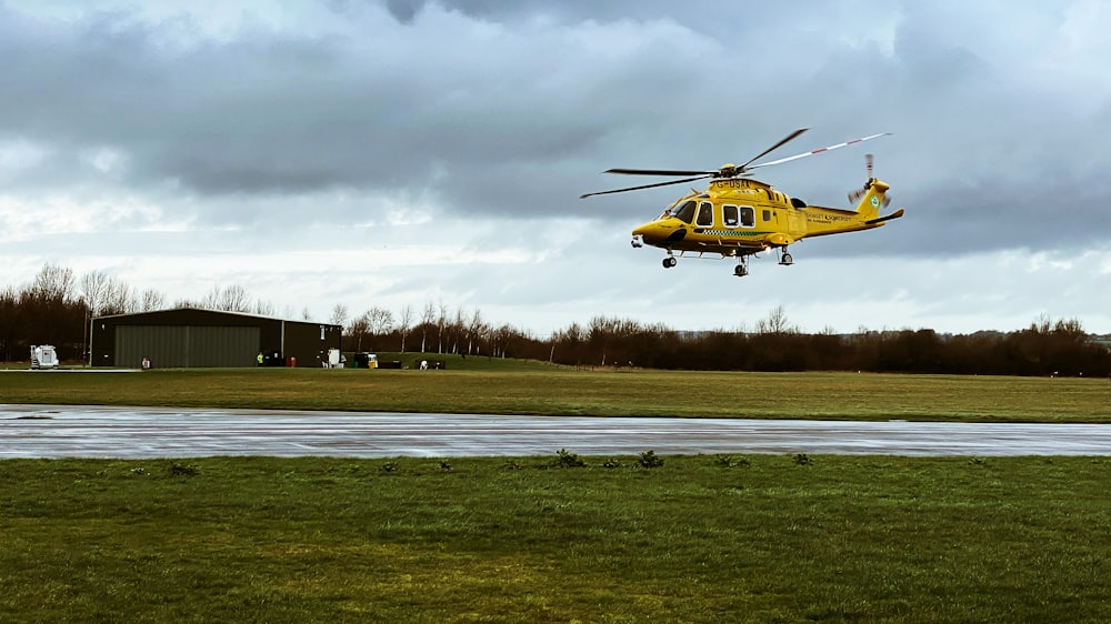 yellow and black helicopter on green grass field under cloudy sky during daytime