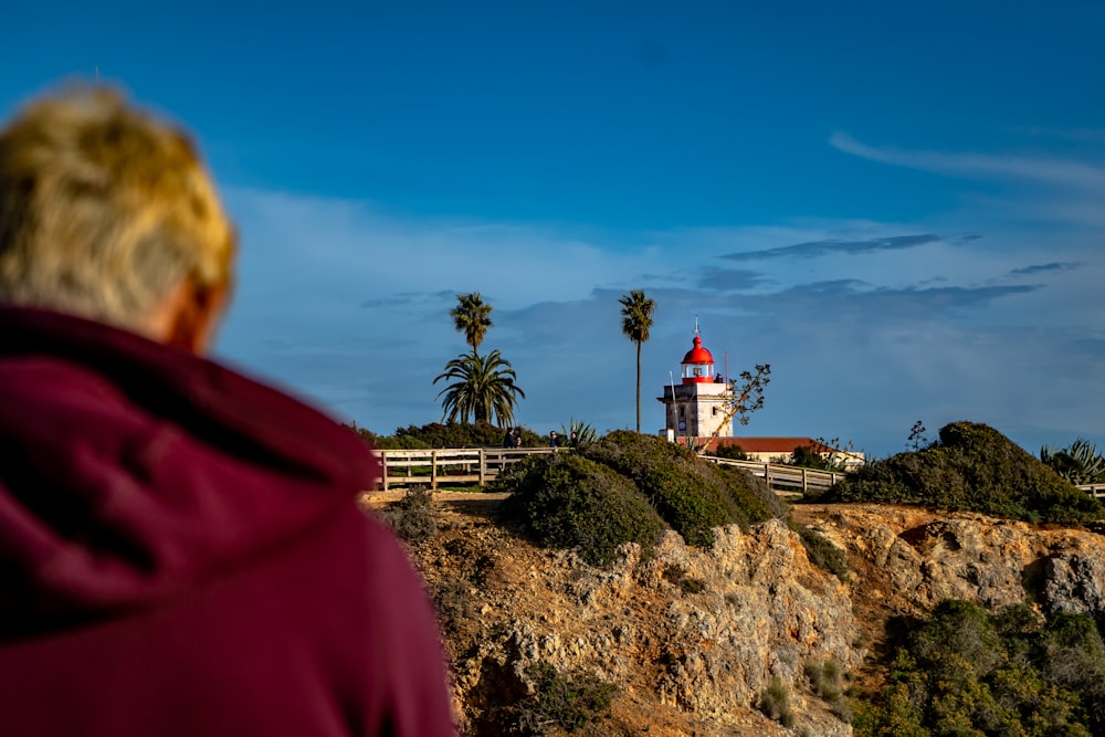 person in red hoodie standing near white and red house during daytime