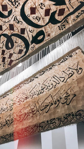 Close-up of a handwoven textile featuring Arabic calligraphy merged with Caribbean island symbols.