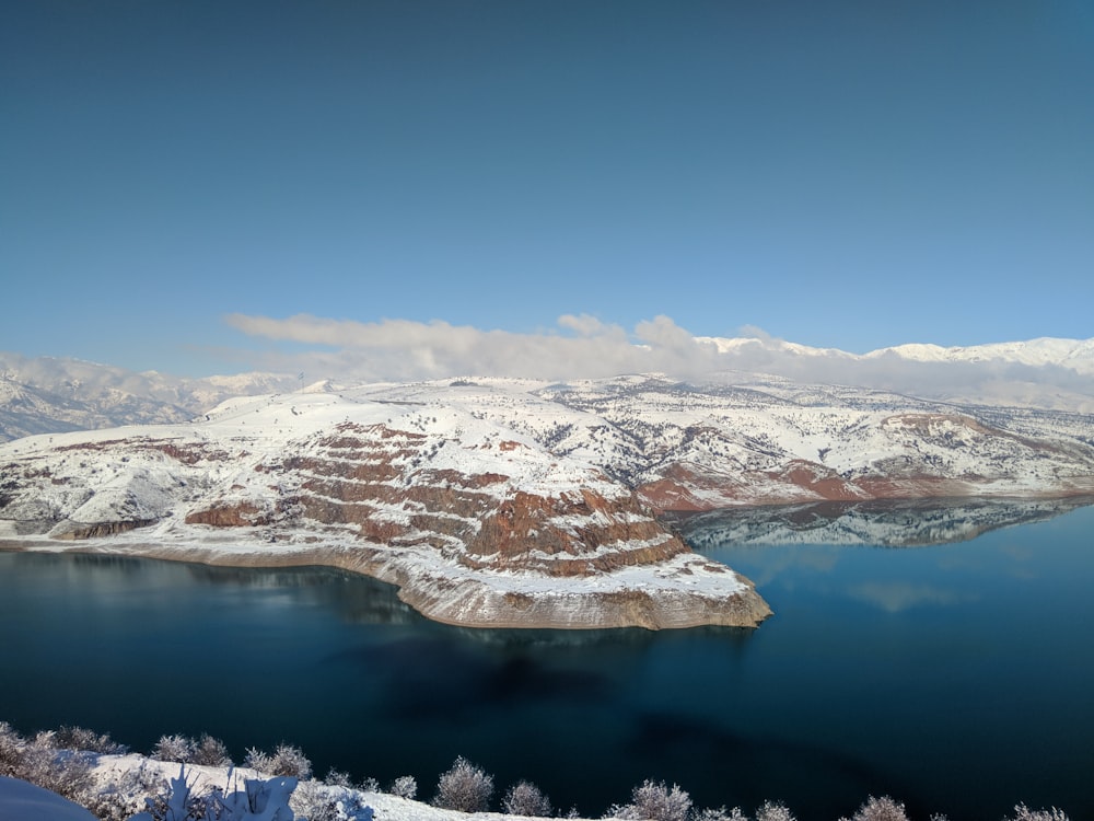 snow covered mountains near body of water during daytime