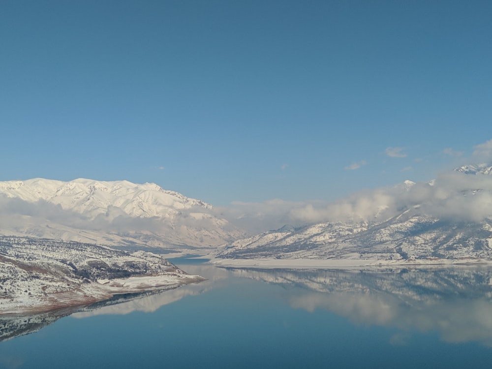 snow covered mountains near lake under blue sky during daytime