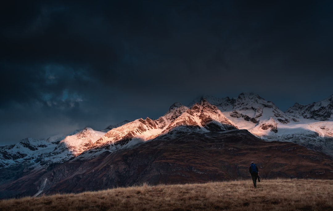 person standing on brown grass field near snow covered mountain during daytime