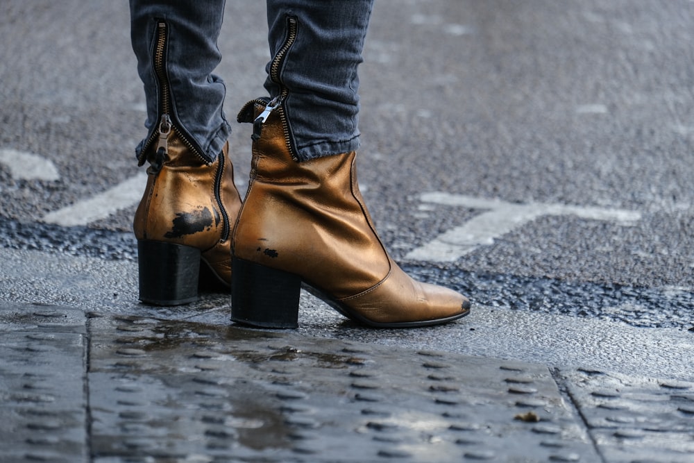 person in brown leather boots standing on gray concrete road during daytime