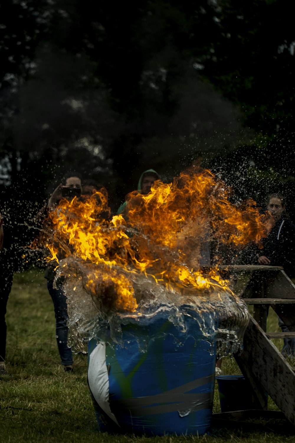 man in blue shirt and blue denim jeans standing in front of bonfire